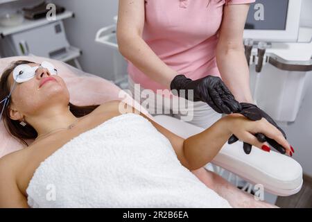 Pelle senza peli, applicazione di gel, epilazione laser, procedura viso cosmetica, cosmetologo applicazione maschera a portata di mano Foto Stock