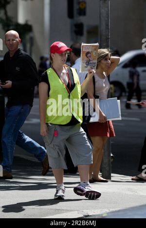 Un venditore di strada che vende The Big Issue, una rivista quindicinale che presenta gli affari attuali, l'intrattenimento, la fotografia e il commento, venduto per le strade di città e città in tutta l'Australia da persone che vivono senza casa o disoccupazione di lunga durata. Aiuta le persone ad aiutare se stesse, poiché i fornitori mantengono la metà del prezzo di copertura di $5 dollari di ogni rivista che vendono. Posizione: All'angolo tra Elizabeth e King Street, Sydney. Foto Stock