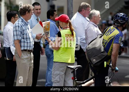 Un venditore di strada che vende The Big Issue, una rivista quindicinale che presenta gli affari attuali, l'intrattenimento, la fotografia e il commento, venduto per le strade di città e città in tutta l'Australia da persone che vivono senza casa o disoccupazione di lunga durata. Aiuta le persone ad aiutare se stesse, poiché i fornitori mantengono la metà del prezzo di copertura di $5 dollari di ogni rivista che vendono. Posizione: All'angolo tra Elizabeth e King Street, Sydney. Foto Stock