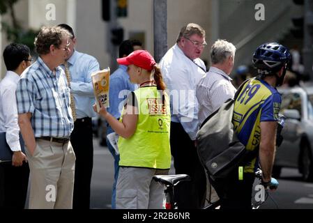 Un venditore di strada che vende The Big Issue, una rivista quindicinale che presenta gli affari attuali, l'intrattenimento, la fotografia e il commento, venduto per le strade di città e città in tutta l'Australia da persone che vivono senza casa o disoccupazione di lunga durata. Aiuta le persone ad aiutare se stesse, poiché i fornitori mantengono la metà del prezzo di copertura di $5 dollari di ogni rivista che vendono. Posizione: All'angolo tra Elizabeth e King Street, Sydney. Foto Stock