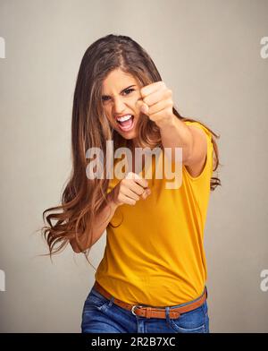La fiducia si distingue per ciò in cui crede. Studio shot di una donna attraente mettere i suoi primi su uno sfondo grigio. Foto Stock