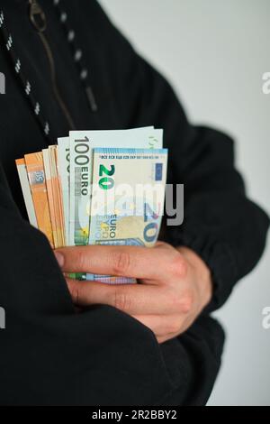 L'uomo tiene il denaro nelle sue mani. Contanti in euro per pagamento o cambio. I maschi contano lo stipendio in banconote in euro. Risparmio di denaro, prelievo di depositi bancari Foto Stock