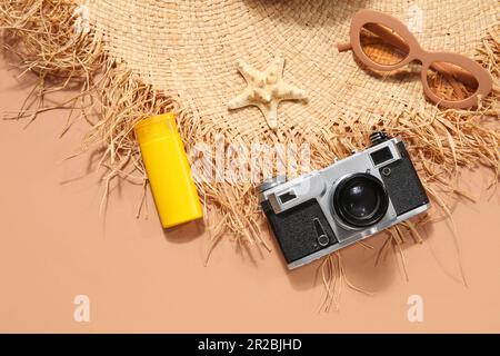 Cappello estivo con crema solare, macchina fotografica, stelle marine e occhiali da sole su sfondo beige Foto Stock