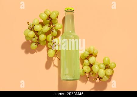 Composizione con bottiglia di soda fresca e uva su fondo beige Foto Stock