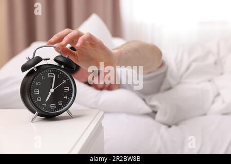 Uomo che spegne la sveglia in camera da letto, concentrarsi sulla mano. Spazio per il testo Foto Stock