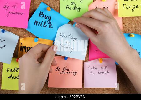 Donna pinning carta nota con frase riunione il Venerdì a sughero bordo, primo piano Foto Stock