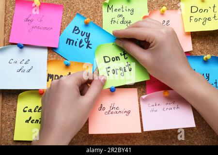 Donna pinning carta nota con frase non dimenticare di sughero bordo, primo piano Foto Stock