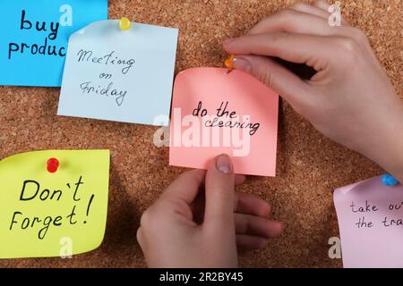 Donna pinning carta nota con frase fare la pulizia a sughero asse, primo piano Foto Stock