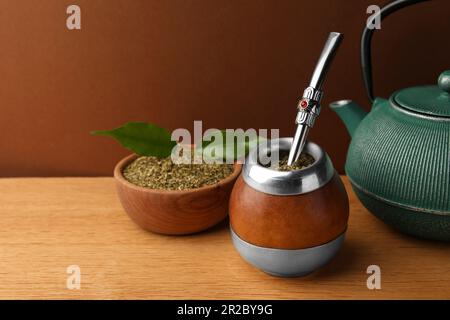 Calabash con tè di mate, bombilla e teiera su tavolo di legno Foto Stock