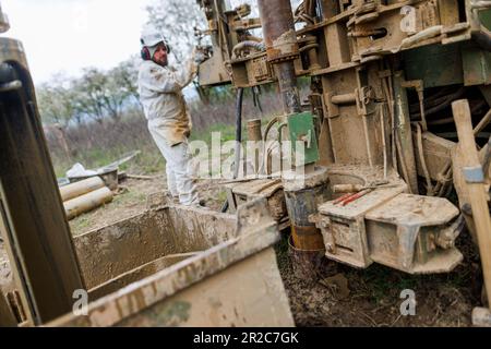 PRODUZIONE - 19 aprile 2023, Baden-Württemberg, Offenburg: Un dipendente di una società di perforazione perfora un tubo nel terreno per prelevare campioni di terreno. Quando la Deutsche Bahn costruisce un nuovo tunnel o interviene in altro modo sul terreno, estrae grandi quantità di materiale scavato dalla terra durante il processo, diversi milioni di tonnellate all'anno solo in Germania. Con una nuova idea di start-up, DB sta restituendo al ciclo economico molte tonnellate di sabbia, ghiaia, argilla e pietra naturale e vuole quindi conservare le risorse: La startup aziendale Erdpool, che offre materie prime minerali provenienti da progetti di costruzione Foto Stock