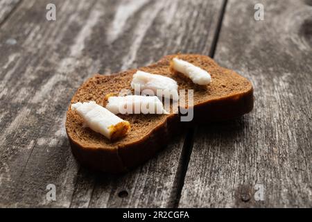 fetta nera di pane con pancetta su un tavolo di legno per il pranzo Foto Stock