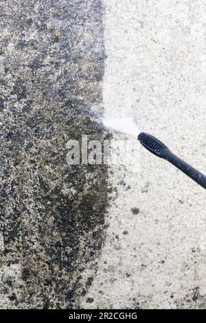 Il lavoratore sta spruzzando acqua per pulire la parete sporca ad alta pressione di pulizia della facciata con una pressione di getto d'acqua Foto Stock