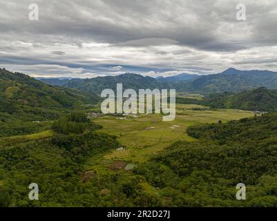 Drone aereo di città in una valle tra terreni agricoli e montagne. Takengon, Sumatra. Indonesia. Foto Stock