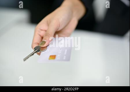 Immagine ravvicinata di un addetto alla reception che fornisce una carta di credito e una chiave della camera a un cliente alla reception. Concetto di check-in in hotel Foto Stock