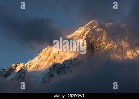 La vetta del Nuptse della regione dell'Everest è avvolta da nuvole al tramonto. Foto Stock