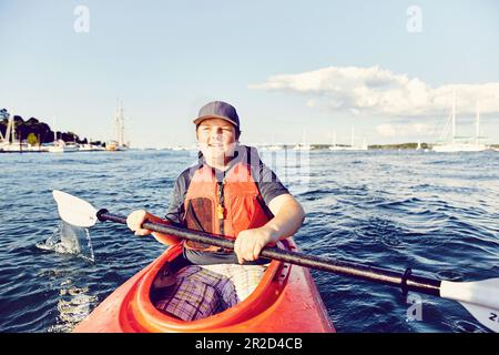 Giovane uomo in kayak al tramonto a casco Bay, Maine Foto Stock