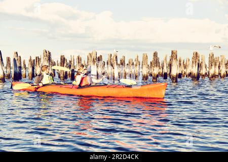 Giovane coppia in un kayak tandem al tramonto a casco Bay, Maine Foto Stock