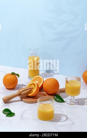 succo d'arancia fresco in un bicchiere e decanter su un tavolo leggero Foto Stock
