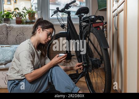 Giovane donna attivista ambientale responsabile e responsabile sta riparando e preparando la sua moto per la primavera e l'estate perché non vuole inquinare Foto Stock