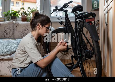 Giovane donna attivista ambientale responsabile e responsabile sta riparando e preparando la sua moto per la primavera e l'estate perché non vuole inquinare Foto Stock