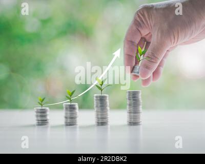 Alberi che crescono su monete. Primo piano delle monete impilabili a mano dell'uomo d'affari con sfondo bokeh verde, Business Finance e Money Concept. investimento a gro Foto Stock