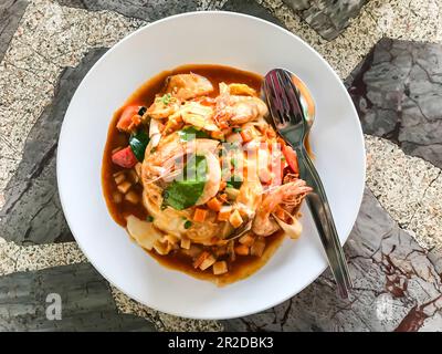 Cibo e posate in piatti bianchi posti su un tavolo di marmo in un ristorante rurale in Thailandia. La cena consisteva di uova, gamberi, coriandolo, kaffir lime lea Foto Stock