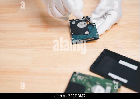correzione e riparazione del computer con disco rigido per il ripristino dei dati e il backup su storage nuovo concetto. Mano del tecnico che tiene il disco rigido o il disco per la riparazione, riparare Ba Foto Stock