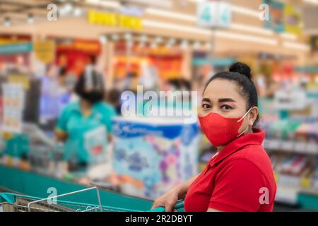 Donne che indossano una maschera Shopping e pagare al banco cassa nel supermercato. Il concetto per il business, finanza, protezione, virus, covid-19. Cl Foto Stock