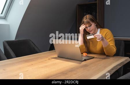 Informazioni rubate nel processo di pagamento. Carta di credito di plastica hold femminile confusa non in grado di accedere al sito web del conto di fatturazione. Donna cleen delusa Foto Stock