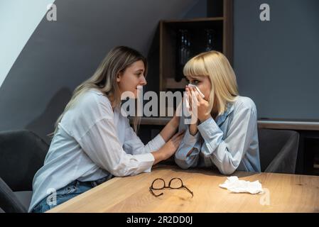 Giovane amica donna confortando la sua triste collega depressa in ufficio che piange dopo un errore al lavoro su un nuovo progetto aziendale ed è sotto stress e fe Foto Stock