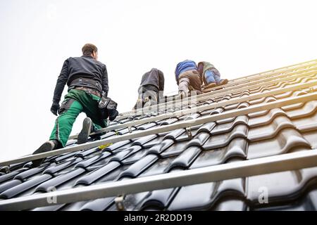 Lavoratori un tetto di una casa che installa pannelli solari Foto Stock
