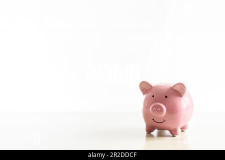 Piggybank di maiali rosa messo su un tavolo di legno. Il concetto per finanza, banca, risparmio, investimento, vendita, Primo piano. Copiare lo spazio a sinistra per des Foto Stock