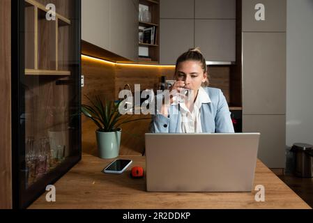 Donna seria dipendente in ufficio seduto sul posto di lavoro, scoldante, dicendo che vi ho detto, guardando il display del notebook mentre si esegue una videochiamata Foto Stock