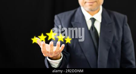 mano di uomo d'affari o di cliente che tiene le stelle per completare cinque stelle per la mente di servizio di soddisfazione. sorride ed è felice prima di dare un ratto a cinque stelle Foto Stock