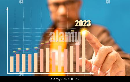 Uomo d'affari che indica la crescita futura del business uomo che punta al top del caricatore 2023, idee per la finanza, le banche, l'economia, il business, interesse, tasso, in Foto Stock