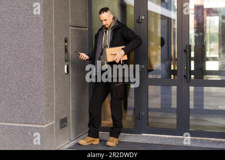 L'uomo utilizza smartphone per aprire la porta della sua casa Foto Stock