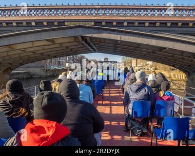 Turisti seduti sul ponte superiore aperto di una barca da crociera fluviale mentre passava sotto un ponte Skeldergate a York. REGNO UNITO Foto Stock