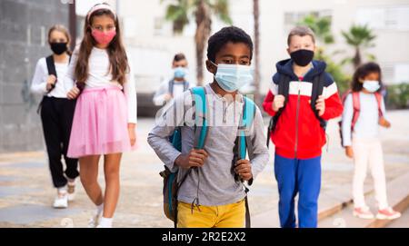 Scolboy afro-americano Tween in maschera protettiva andare a scuola Foto Stock