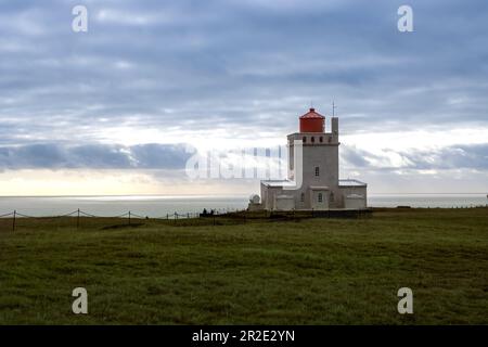 Vista sul faro e sull'oceano Atlantico. Intense nuvole piovose in autunno. Dyrholaey, Islanda. Foto Stock