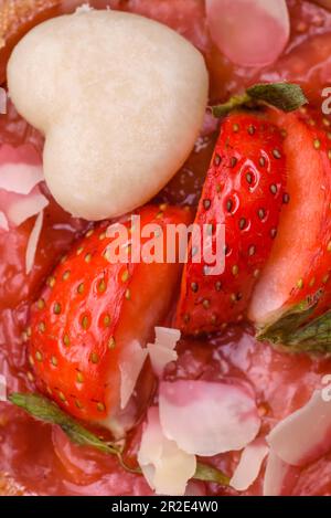 Deliziose tartine dolci fresche con fragole e fiocchi di cocco su fondo di cemento scuro Foto Stock