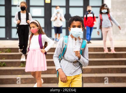 Scolboy afro-americano Tween in maschera protettiva andare a scuola Foto Stock