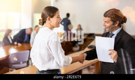Manager bianco di mezza età che dà il benvenuto a una nuova dipendente bianco femminile Foto Stock