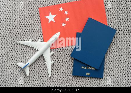 Bandiera della Cina con passaporto e aereo giocattolo. Concetto di viaggio in volo. Foto Stock