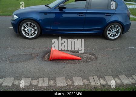 Dorney, Buckinghamshire, Regno Unito. 19th maggio, 2023. Anche se alcuni buche sono state patched nel vicino villaggio rurale di Dorney REACH nel Buckinghamshire oggi, ci sono ancora un certo numero di buche sulla strada comune nel Dorney Village che hanno ancora bisogno di riparare. Questo ha un cono di avvertimento da esso ma continua ad essere bussato sopra passando il traffico. Buckinghamshire ha migliaia di buche non riparate che vengono lentamente applicate con una nuova macchina Velocity Patcher. Credit: Maureen McLean/Alamy Live News Foto Stock