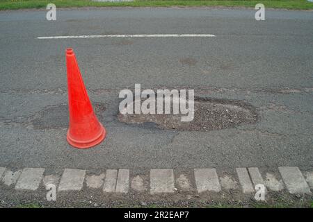 Dorney, Buckinghamshire, Regno Unito. 19th maggio, 2023. Anche se alcuni buche sono state patched nel vicino villaggio rurale di Dorney REACH nel Buckinghamshire oggi, ci sono ancora un certo numero di buche sulla strada comune nel Dorney Village che hanno ancora bisogno di riparare. Questo ha un cono di avvertimento da esso ma continua ad essere bussato sopra passando il traffico. Buckinghamshire ha migliaia di buche non riparate che vengono lentamente applicate con una nuova macchina Velocity Patcher. Credit: Maureen McLean/Alamy Live News Foto Stock