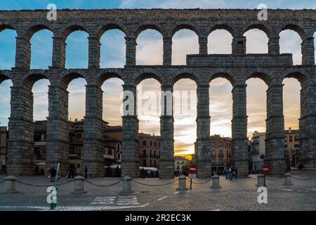 Veduta dell'acquedotto di Segovia. Sensazionale tramonto arancione, visto attraverso gli archi dell'acquedotto. Destinazione turistica di Castilla e Leo Foto Stock