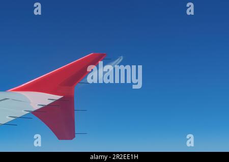 Vista di un'ala di un aeroplano durante il volo e dell'aeroplano in arrivo in distanza. Concetti di aviazione, aerodinamica e traffico aereo Foto Stock