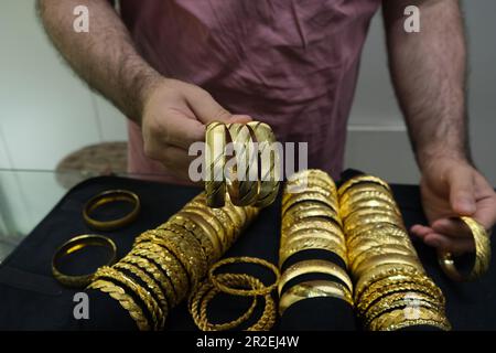 Il venditore mostra tre braccialetti dorati in un negozio di gioielli in Turchia. Foto Stock