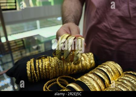 L'uomo di vendite mostra tre bracciali d'oro di lusso di imitazione ad un deposito dei monili. Foto Stock