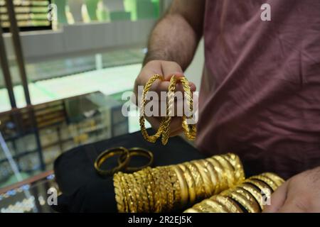 Braccialetti d'oro di lusso, l'uomo di vendita mostra tre bracciali d'oro d'imitazione in gioielleria. Foto Stock